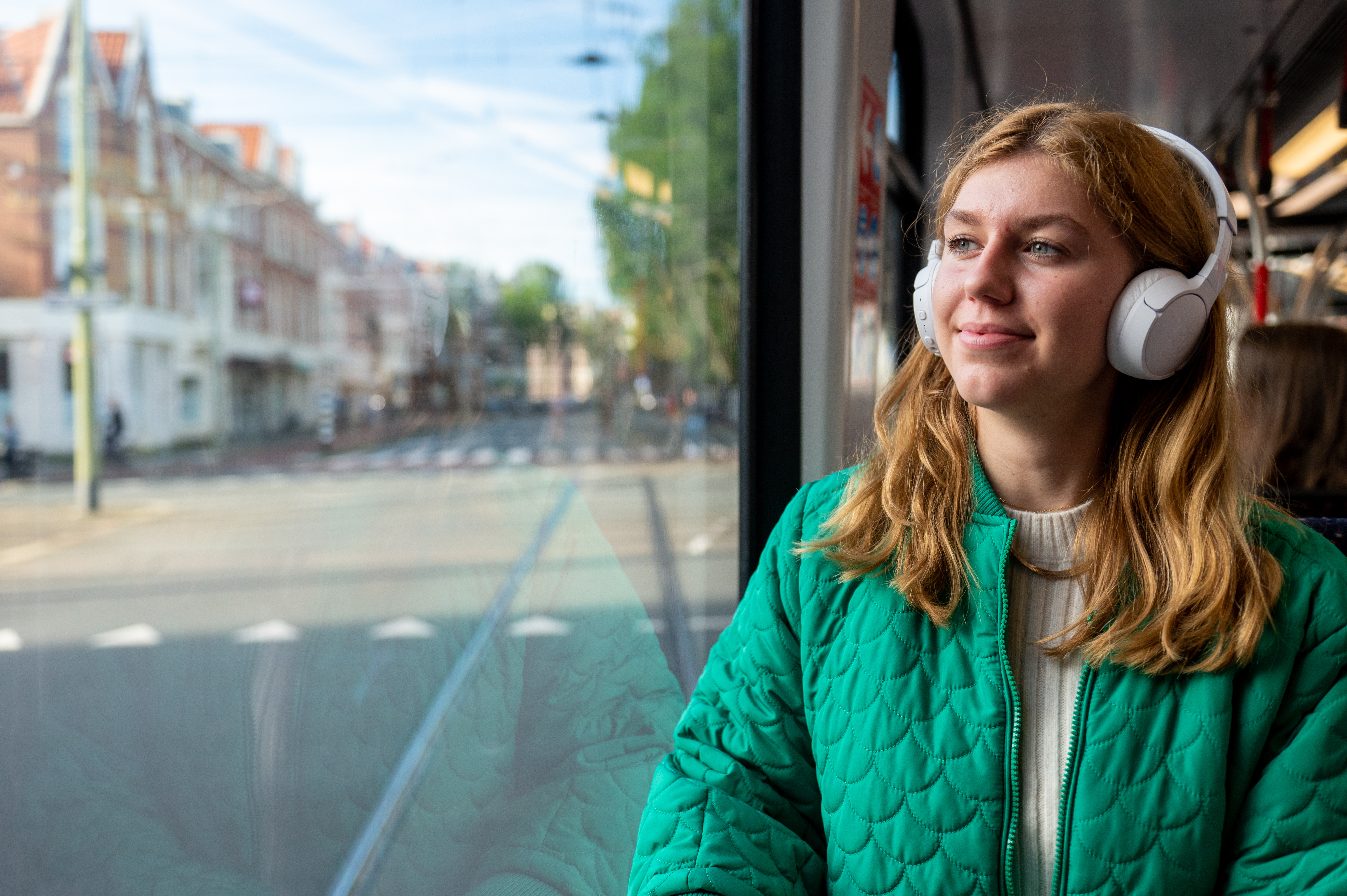Vrouw zit in HTM tram en luister muziek met koptelefoon op