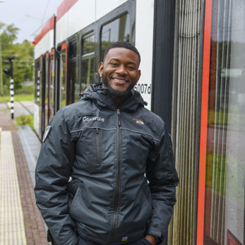 BOA controleur staat naast tram HTM BOA controleur staat naast HTM tram en lacht naar de camera