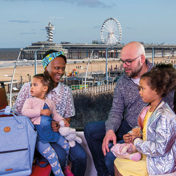 HTM Meivakantie Strand Gezin met kinderen zit in HTM tram met uitzicht op Scheveningen