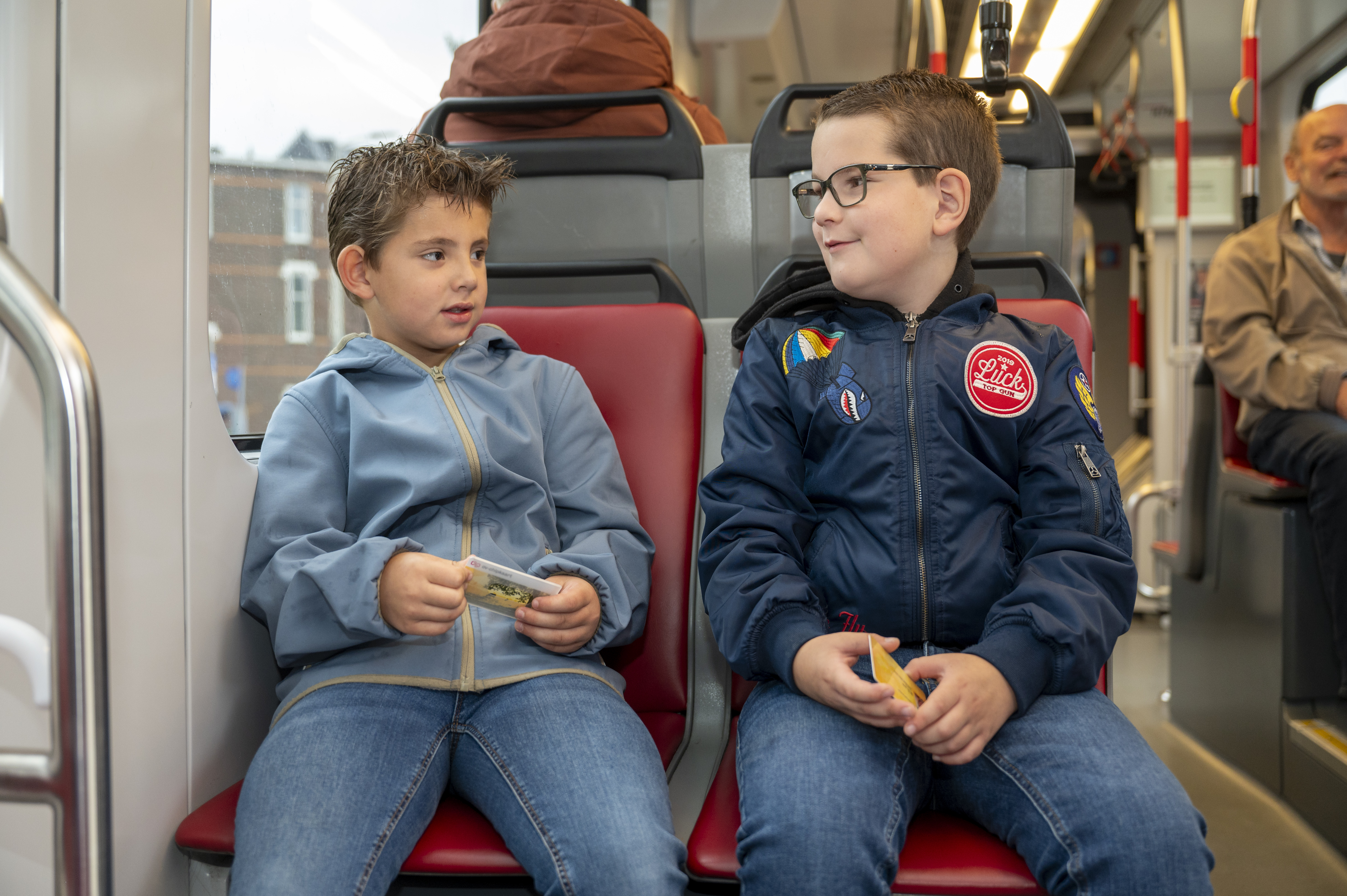 twee jongens zitten in de tram en houden een OV-chipkaart vast