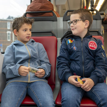 twee jongens zitten in de tram en houden een OV-chipkaart vast twee jongens zitten in de tram en houden een OV-chipkaart vast