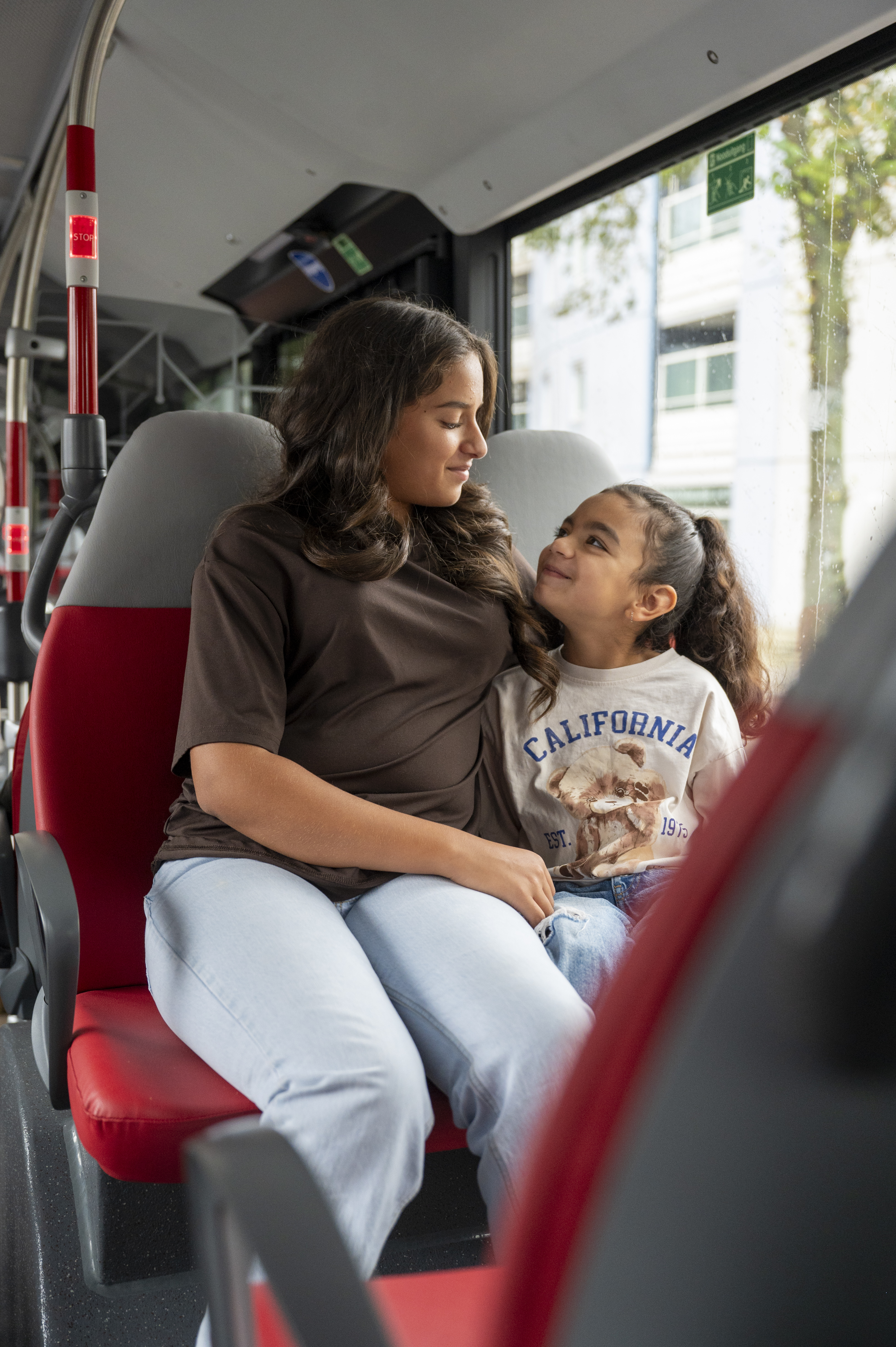 Moeder en dochter zitten samen in de bus kijken lachend naar elkaar