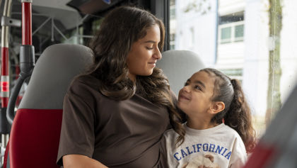 Moeder en dochter zitten samen in de bus kijken lachend naar elkaar Moeder en dochter zitten samen in de bus kijken lachend naar elkaar