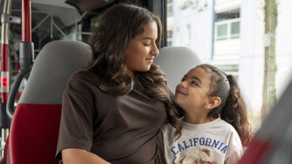 Moeder en dochter zitten samen in de bus kijken lachend naar elkaar Moeder en dochter zitten samen in de bus kijken lachend naar elkaar