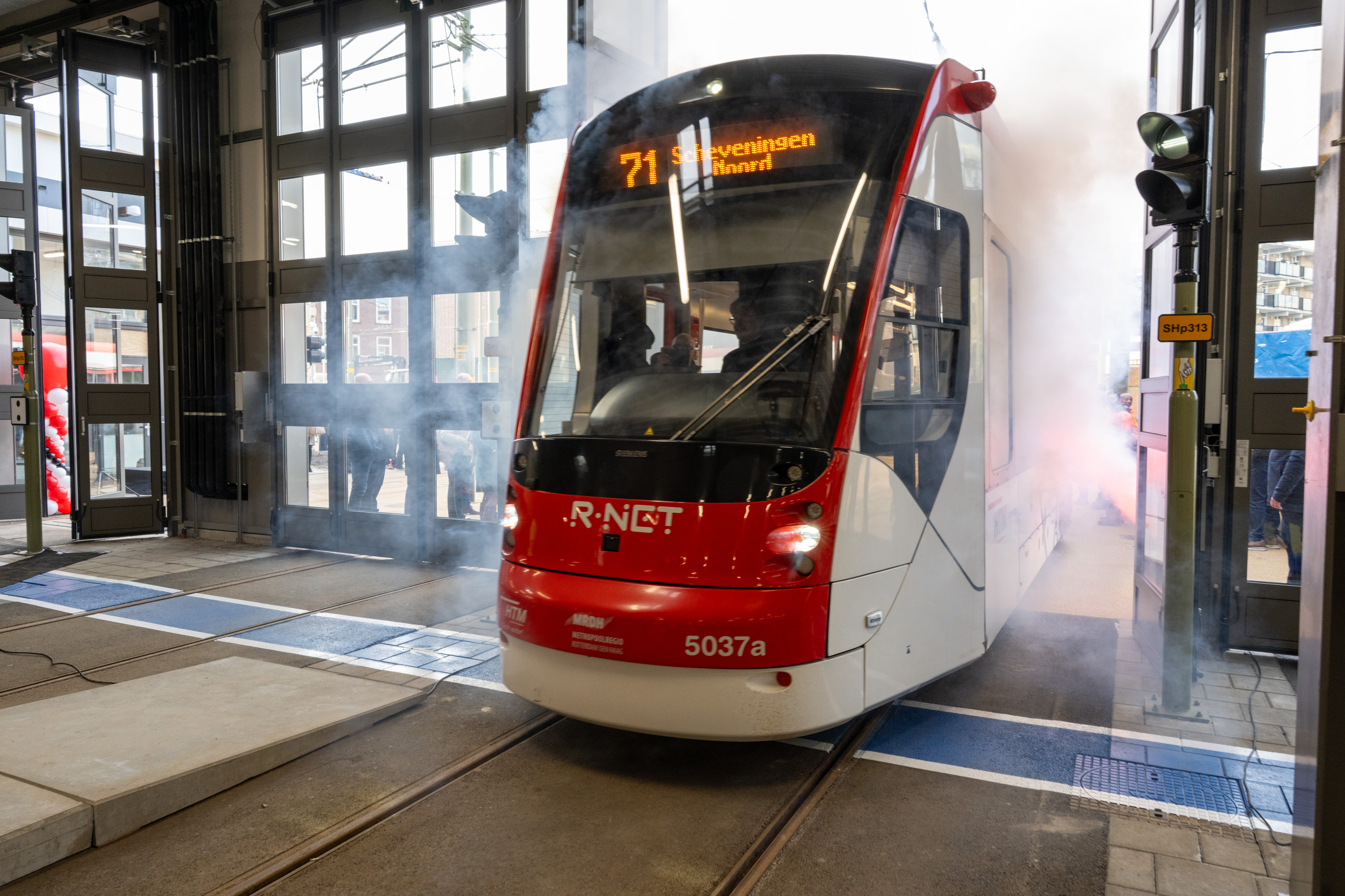 Een Avenio-tram van HTM rijdt door een rookgordijn de vernieuwde remise in