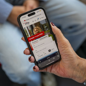 Reiziger Met Mobiel in haar hand waarop je de htm website ziet Reiziger Met Mobiel in haar hand waarop je de htm website ziet