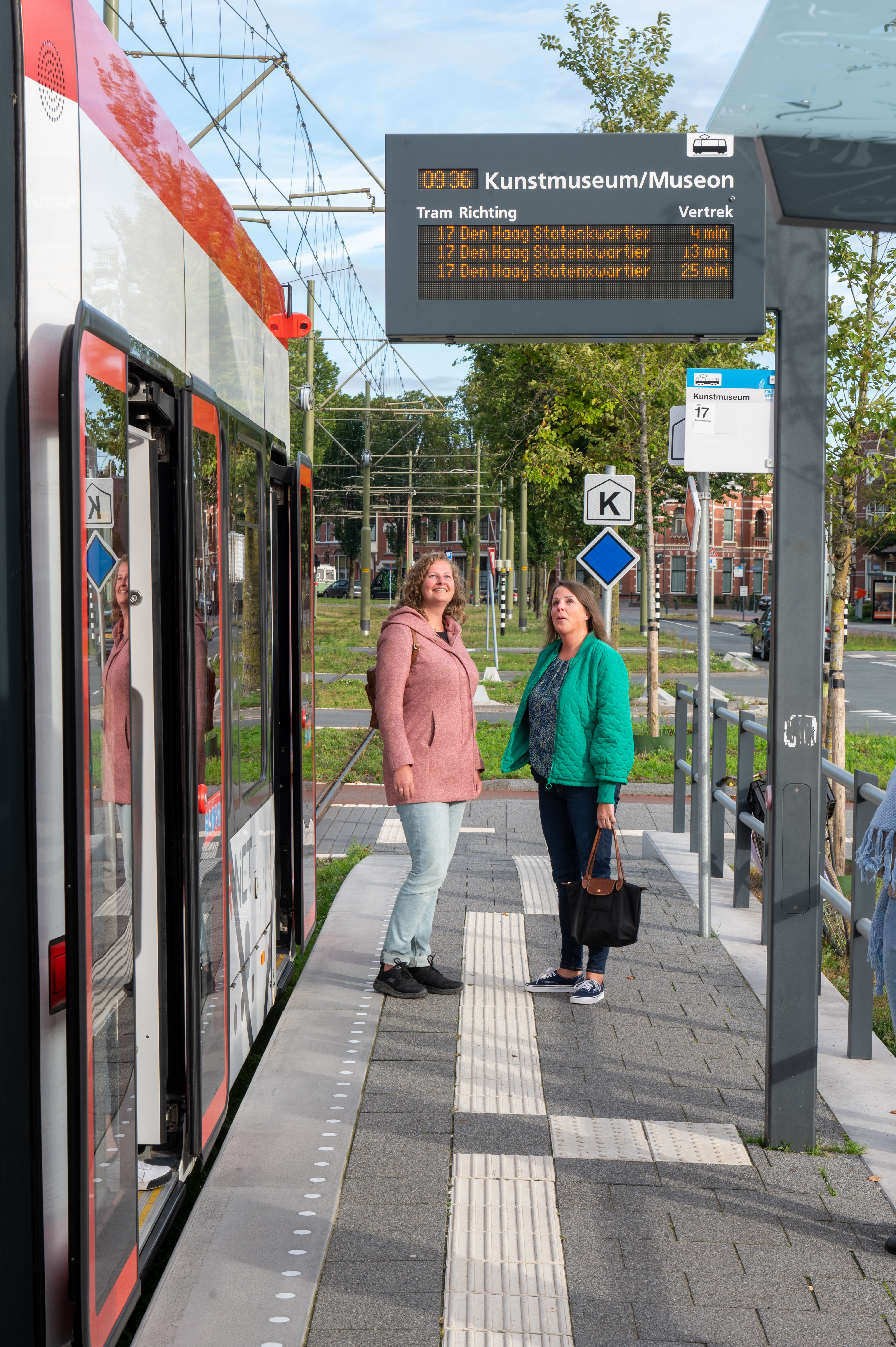 Reizigers staan op halte naast HTM tram